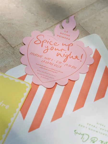 Wedding invitation suite with die cut wedding invitation, flame-shaped card and striped envelope liner arranged on a stone surface