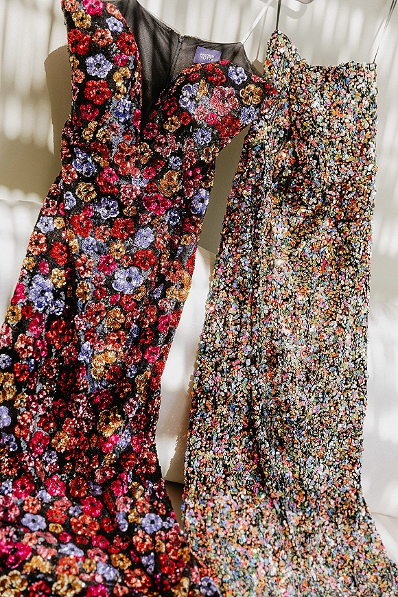 Bridesmaid dresses, sequin bridesmaid dress styles, hang on dress hangers with floral patterns in window light against a white wall