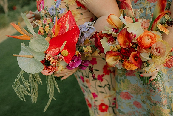 Wedding bouquets with tropical wedding bouquet blooms—anthurium, orchids, tulips, roses, calla lilies and greenery on a grass lawn