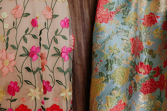 Bridesmaid dresses in mismatched bridesmaid dresses styles, showcasing floral embroidery and brocade textures against a wood panel wall