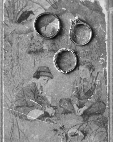 Wedding rings with an engagement ring and bands, including a diamond eternity band, arranged on a vintage illustrated book page backdrop