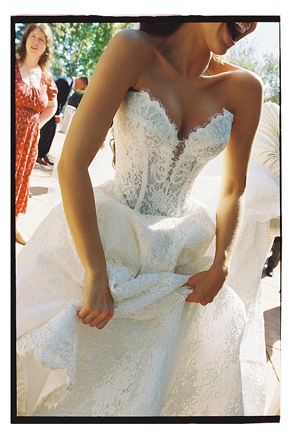 Wedding dress with strapless lace wedding dress bodice, sweetheart neckline and floral lace over tulle skirt on an outdoor patio by trees