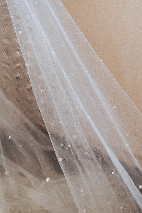 Wedding veil with pearl wedding veil detailing, sheer tulle fabric dotted with pearls against a clean neutral backdrop