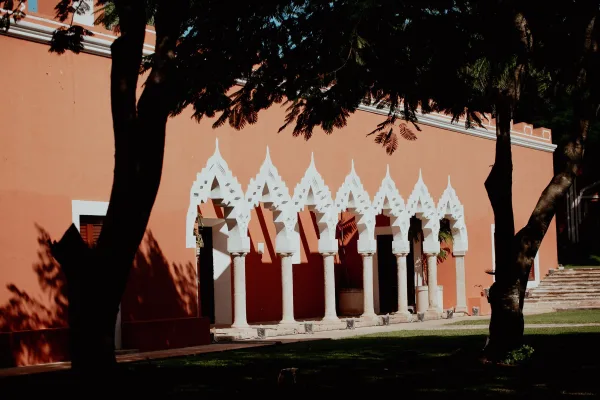 Wedding venue exterior with an arched colonnade of white columns and decorative arches against a terracotta stucco wall and lawn