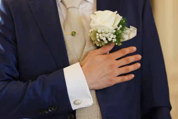Groom boutonniere featuring a white rose boutonniere neatly pinned to a tailored suit jacket, its soft petals arranged in a classic style.