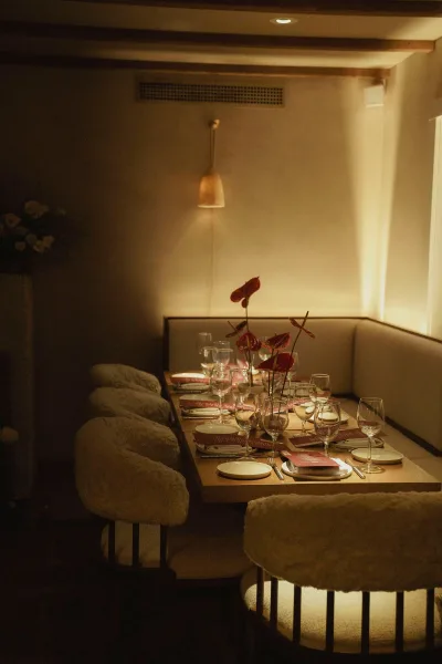 Reception tablescape with an intimate wedding dinner table place setting, red anthurium centerpiece, menus, and glasses under pendant lights in a cozy booth
