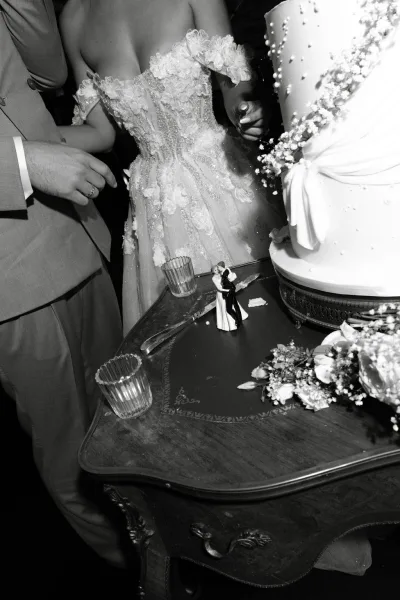 Wedding cake cutting captured as the couple’s hands make the first slice, showing cake knife detail against a classic white cake.