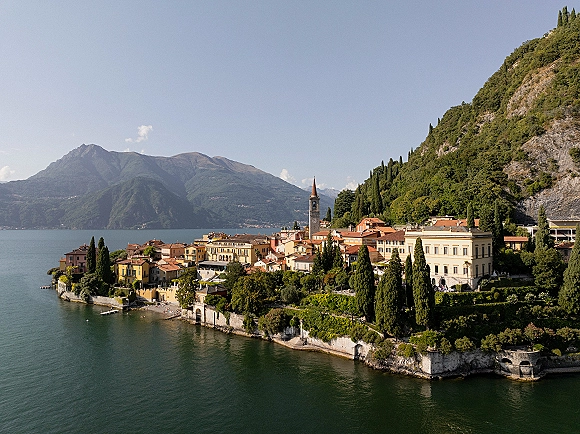 Lake wedding venue overlooking a mountain lake, with terraced gardens, cypress trees, and a church bell tower among historic buildings.