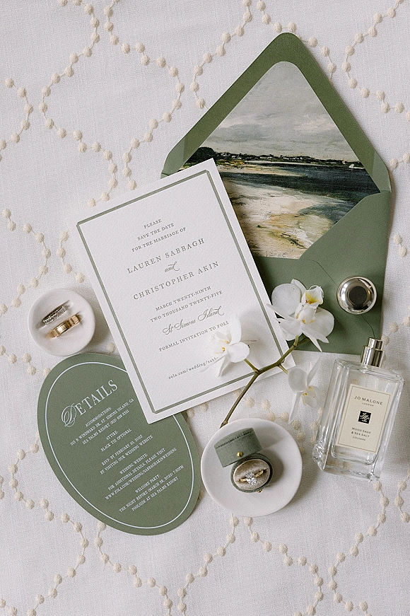 Invitation suite wedding invitation flat lay with save the date, green envelope, wax seal, rings and orchids on embroidered linen background