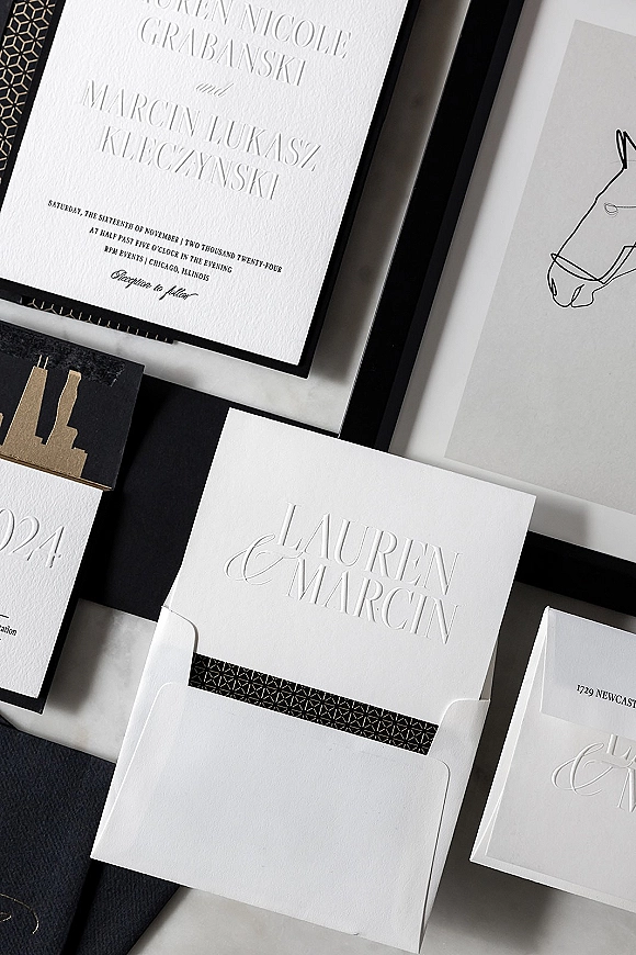 Invitation suite with embossed wedding invitations, letterpress card, RSVP and monogram details with black geometric liner on white surface