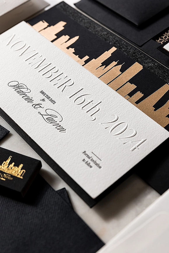Wedding invitation suite with black and gold wedding invitations, letterpress and calligraphy cards with black envelope on a white tabletop flat lay