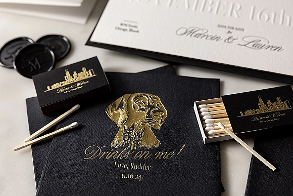 Wedding invitation suite with black and gold wedding invitations, gold foil and embossed lettering, envelopes and wax seals on a white tabletop