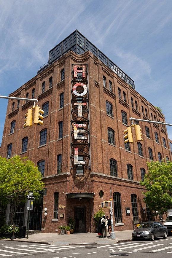 Wedding venue exterior with an industrial wedding venue brick facade, vertical neon sign, and crosswalk on a sunny city street