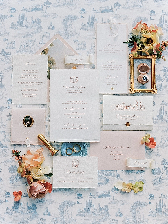 Invitation suite with deckled edge wedding invitations, calligraphy cards and wax seal on blue toile fabric, accented by rose petals