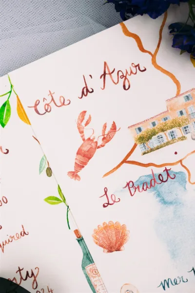 Wedding invitation suite featuring a watercolor wedding invitation with a lobster accent, set on tulle with blue flowers.