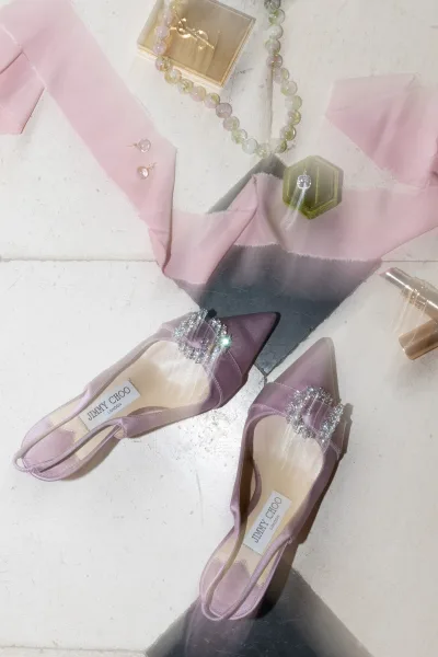Bridal shoes, lilac wedding heels styled with a single ring box, arranged neatly on a black tile floor.