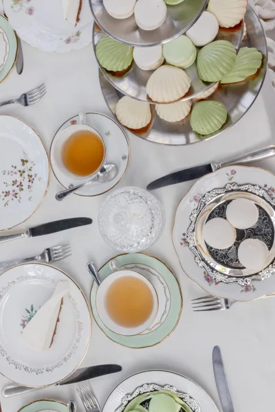 Tea party tablescape with a vintage china table setting, centered on a tiered dessert stand displaying neatly arranged petite sweets.