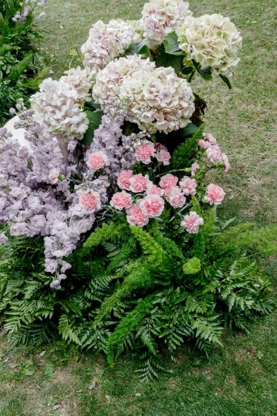 Wedding floral arrangement serving as outdoor wedding flowers on a grass lawn, hydrangeas clustered amid lush garden foliage.
