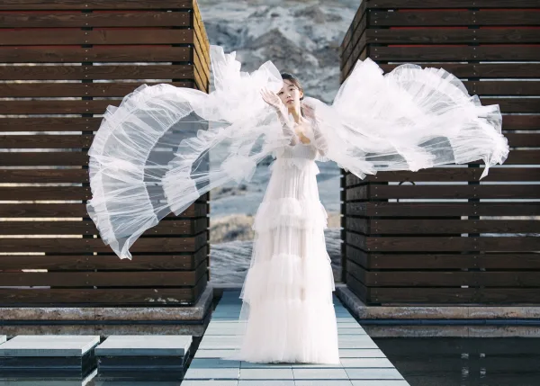 Bridal portrait of a bride in a white wedding dress with a long tulle veil flowing over a tiled walkway with mountains behind