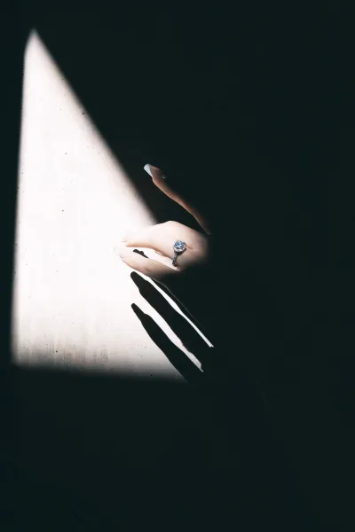 Engagement ring solitaire engagement ring sparkling on manicured hand, diamond catching window light against a shadowed wall and dark space