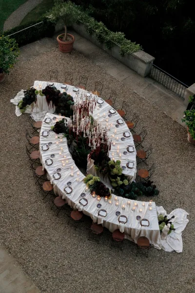 Reception tablescape showcasing outdoor reception decor with glimmering candelabras along a table in a gravel courtyard.