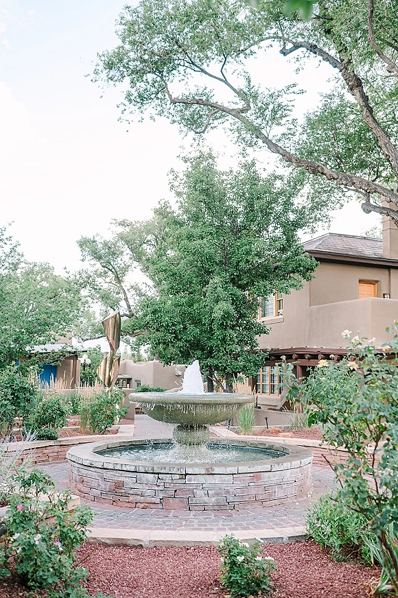 Courtyard fountain in a wedding venue courtyard, with a stone tiered water feature on brick pavers surrounded by garden shrubs and flowers