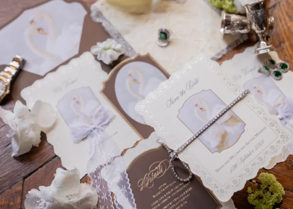 Wedding invitation suite with matching save the date card, styled with lace in a tidy flat lay on a wood tabletop