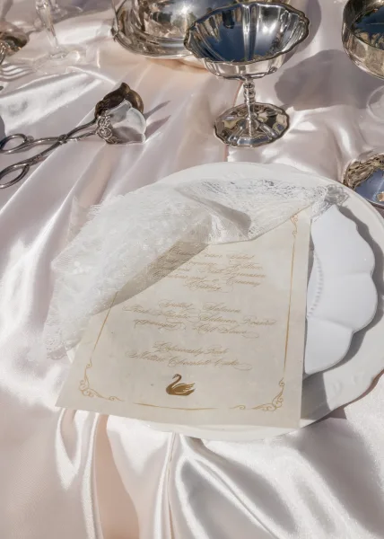 Wedding menu with a script menu card layered over delicate lace fabric, styled for an elegant place setting.