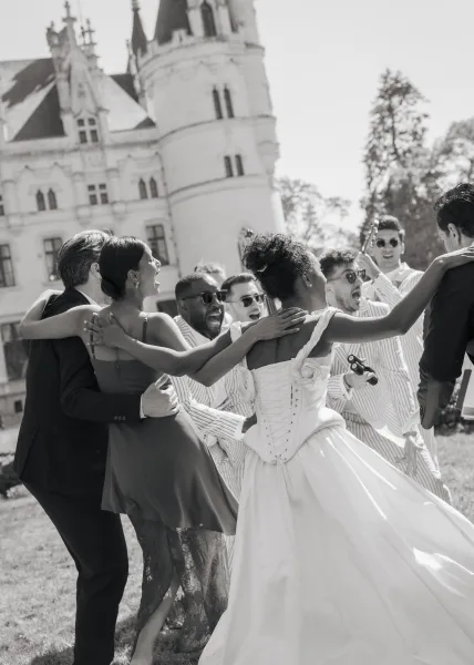 Wedding party moment with a bride with her wedding party laughing on a castle lawn, corset back gown catching light amid cheering friends.
