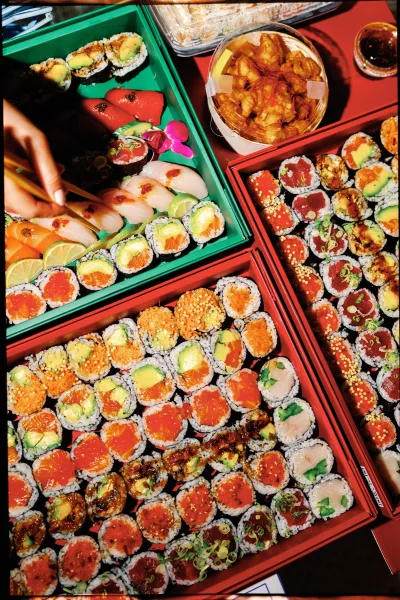 Sushi catering wedding sushi bar spread with assorted rolls and nigiri on platter trays, topped with microgreens and edible flowers on a tabletop