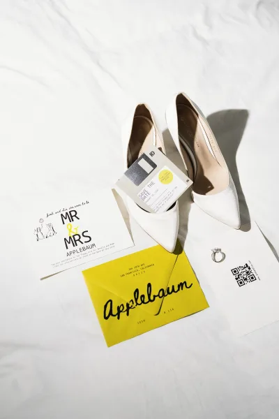 Invitation suite wedding invitation flat lay with yellow envelope, RSVP and save the date cards, QR code, floppy disk, ring and white heels on fabric