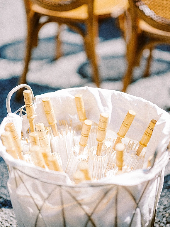 Wedding sparklers for a sparkler send off arranged in a metal basket with wooden handles and white tissue paper on carpet by chairs
