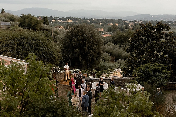 Wedding cocktail hour with outdoor cocktail hour lounge seating, white sofas and drinks under string lights on a stone terrace with mountain views