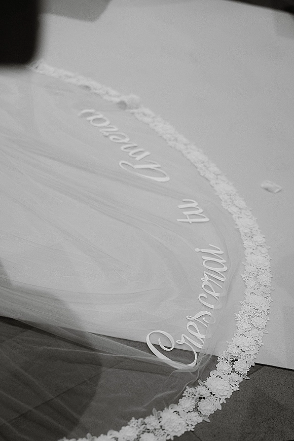 Wedding veil with lace edge trim and personalized embroidered lettering displayed in a flat lay on a smooth fabric surface