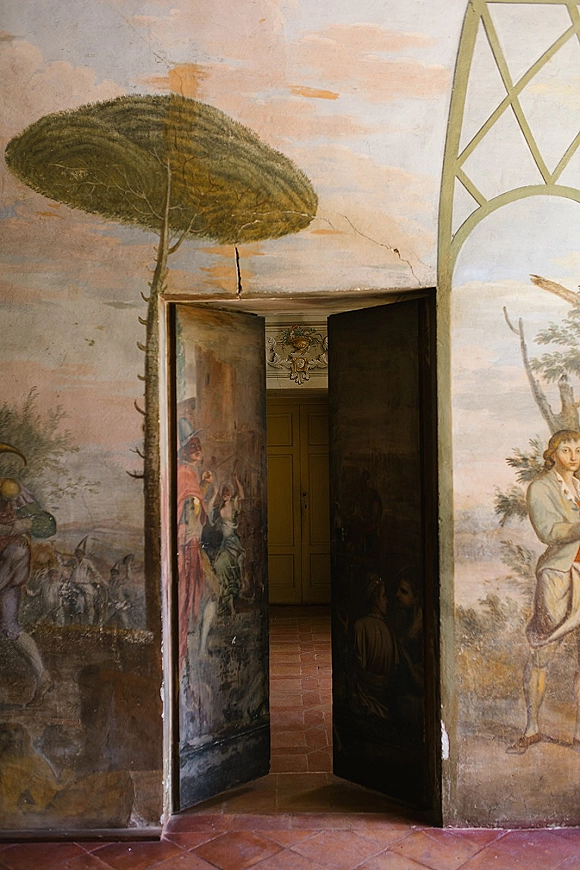 Vintage door backdrop with antique painted doors and a hand-painted fresco mural, crest emblem, and arched hallway on terracotta tiles