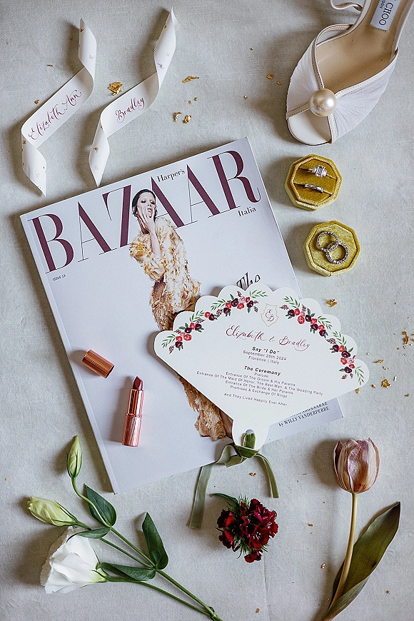Invitation suite wedding invitation flat lay with floral print card, silk ribbon, rings in boxes, pearl heel, tulips on linen backdrop