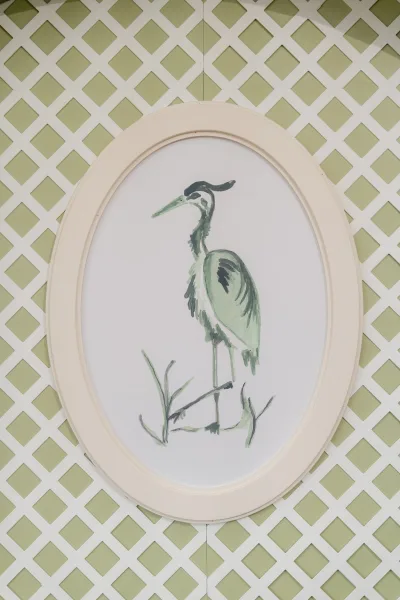 Wedding wall decor featuring bird wedding decor in an oval frame, with watercolor heron artwork on a green lattice patterned wall