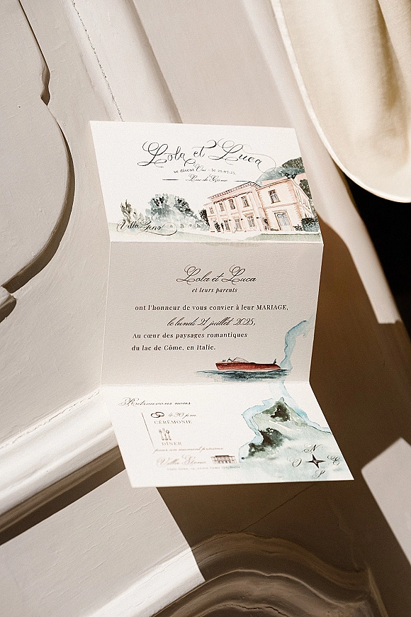 Wedding invitation with watercolor wedding invitation design, folded card in calligraphy and a boat illustration on a sunlit white window sill