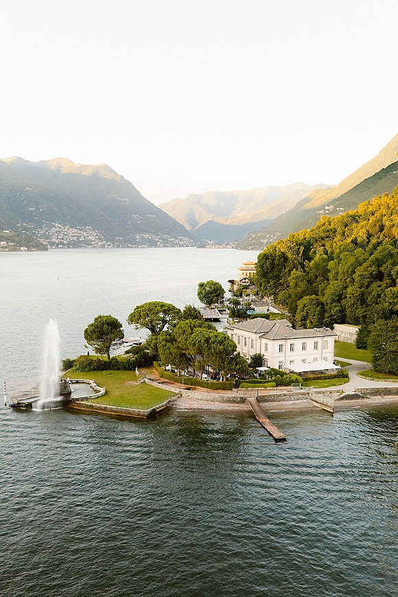 Wedding venue on a lake wedding venue with villa terrace, fountain and dock, set on a green lawn with mountains beyond the shoreline