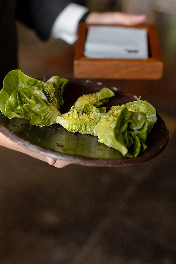 Wedding appetizers of lettuce wraps on a ceramic serving plate, arranged on a food service tray in an indoor venue with dark flooring