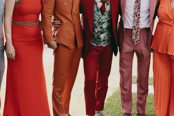 Wedding party portrait in colorful wedding party outfits, highlighted by a standout floral vest as the group poses together.