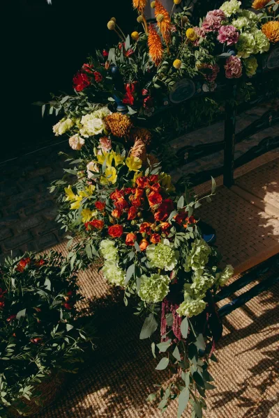 Wedding floral arrangement of colorful wedding flowers with amaranthus trailing over a jute rug beside a cobblestone path.