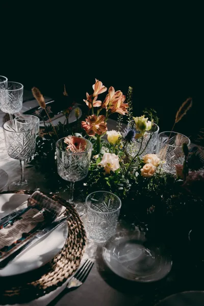 Reception tablescape featuring wedding table decor with crystal glassware, set against a moody dark backdrop.