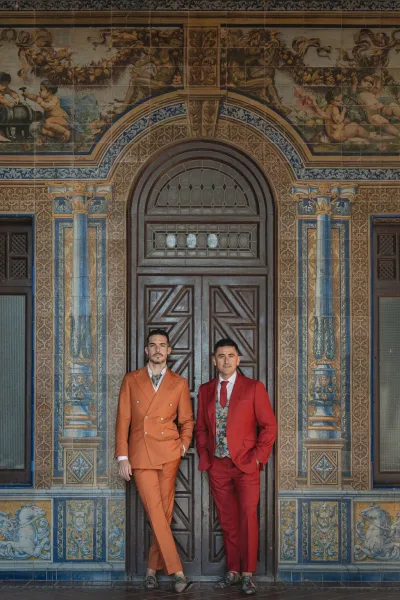 Grooms portrait showcases colorful groom suits with floral ties against an ornate tiled wall and arched wooden door.