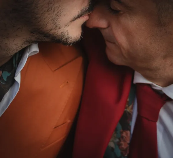 Couple portrait of two grooms leaning close in tailored suits, captured as a tender, intimate wedding moment.