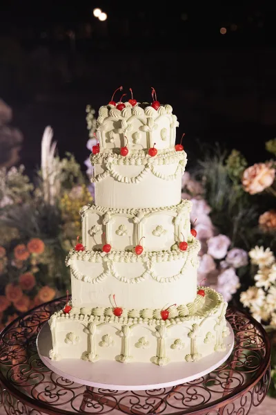 Wedding cake, a towering Lambeth wedding cake crowned with cherries, displayed outdoors on a garden table under a starry night sky.