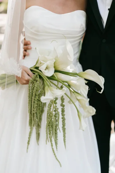 Bridal bouquet, a sleek calla lily bouquet with trailing amaranthus, elegantly held by the bride, styled in a modern, minimal design.
