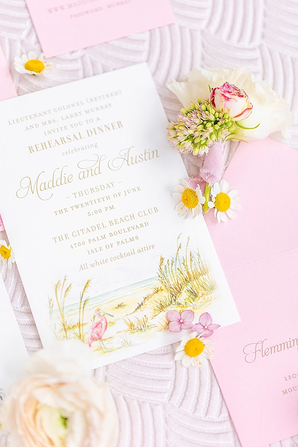 Invitation suite wedding invitation flat lay with pink envelopes, ribbon wrap, wax seal and floral boutonniere on textured white fabric