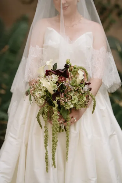 Bridal bouquet, a cascading wedding bouquet with trailing greenery, set against soft garden foliage.