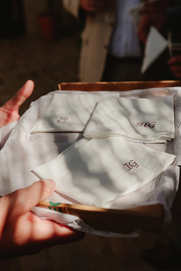 Wedding handkerchiefs in a gift box, embroidered monogram linen squares wrapped in tissue paper, held in hands indoors
